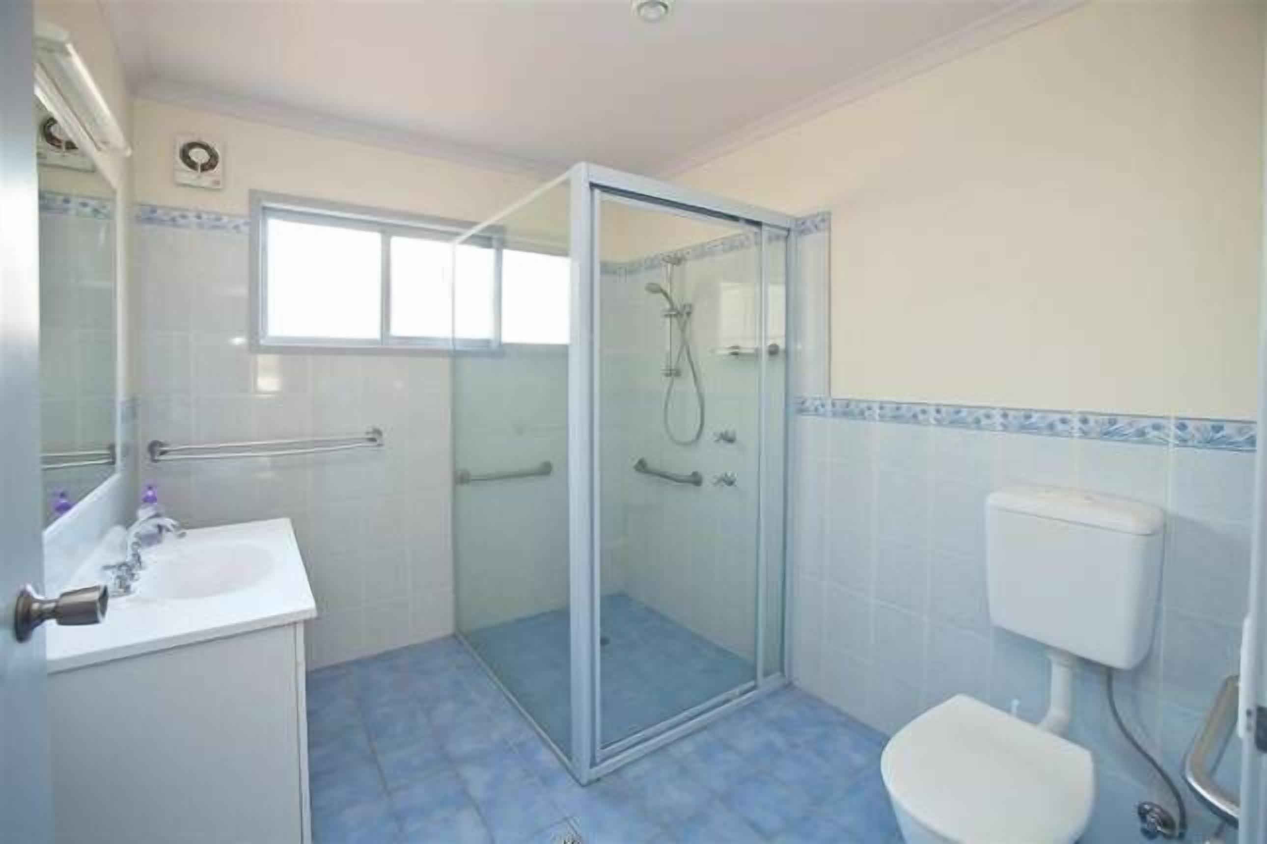 Un baño con cabina de ducha de vidrio, un lavabo blanco y un inodoro.