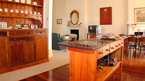A spacious living room with a wooden coffee table, a fireplace, a television, and a dining area with chairs and a table. - Fire Station Inn Penthouse Spa Apartment (North Adelaide)