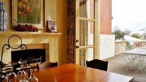 A dining area with a wooden table and chairs, a fireplace, and a view of the outside. - Fire Station Inn Penthouse Spa Apartment (North Adelaide)