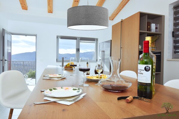 A dining table set with plates, cutlery, wine glasses, and a bottle of wine.