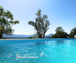 Une piscine d’eau bleue et limpide, avec une vue sur les montagnes en arrière-plan.