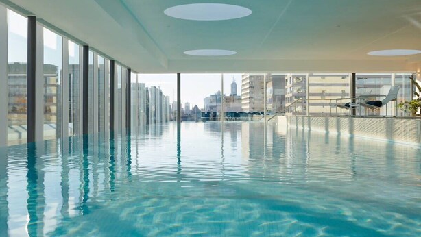 An indoor swimming pool with clear water, large windows, and a city view. - Fawkner Residence 1B1B Condo with Pool&Gym Access (Melbourne)