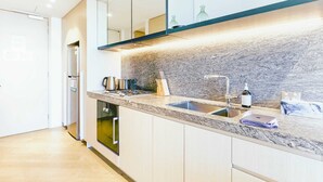 A modern kitchen with a granite countertop, stainless steel appliances, and a built-in oven. - Fawkner Residence 1B1B Condo with Pool&Gym Access (Melbourne)