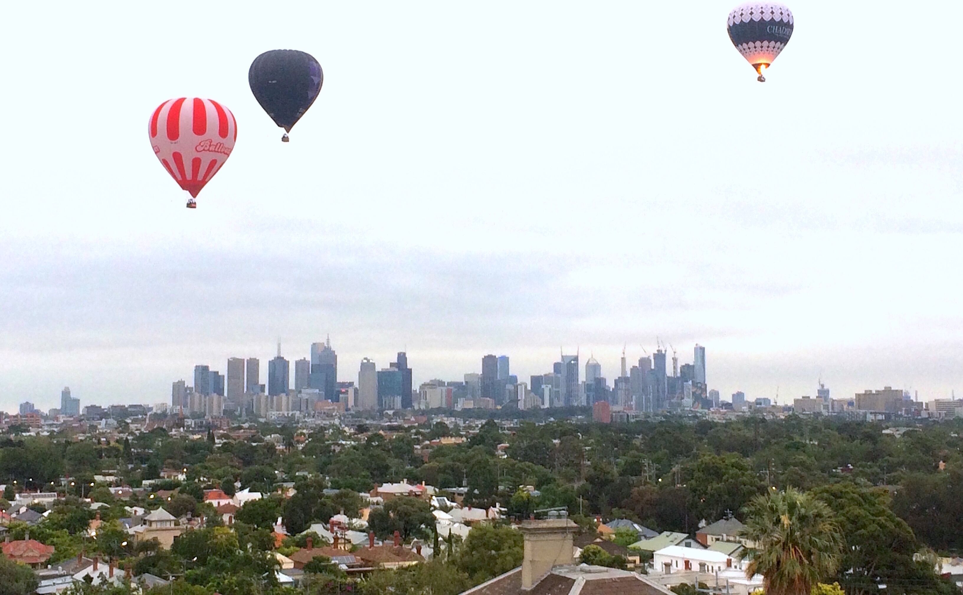 Stadsbeeld met luchtballonnen in de lucht.
