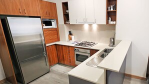 Eine kleine Küche mit Kühlschrank, Mikrowelle, Herd, Backofen und Spüle.