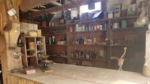 A rustic kitchen with wooden shelves stocked with various canned goods, jars, and kitchen utensils. - Devcich Historic Farmstead - Cottage (Thames)