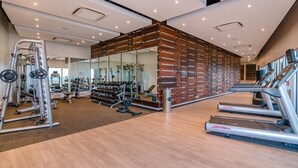 Un gimnasio moderno con cintas de correr, máquinas de pesas y un muro con espejos.