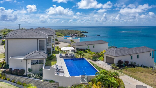 Zona residencial con piscina, casas y vista al océano.