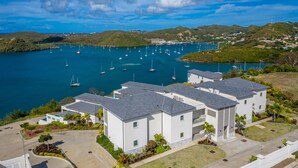 Una zona residencial con casas modernas, un puerto deportivo con veleros y un paisaje montañoso al fondo.