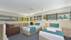 A hotel room with two beds, a sofa, and large windows with a view of palm trees. - Driftwood Mantaray Three Bedroom Loft (Douglas)