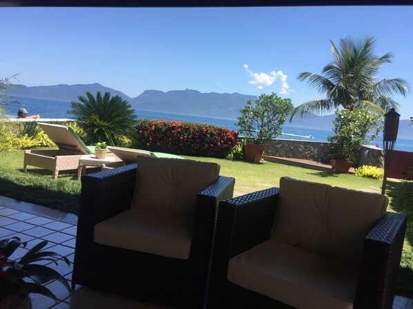 A patio with wicker chairs and a view of the ocean.