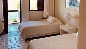 A hotel room with two beds, a window with curtains, a ceiling light, a bedside table with a lamp, and a framed picture on the wall. - Paradise House - Angra dos Reis (Conceição de Jacareí)
