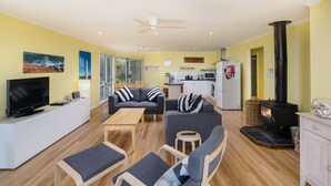 Un salon moderne avec un canapé, des fauteuils, un téléviseur et une cheminée.