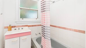 Ein Badezimmer mit einem weißen Waschbecken, einem Spiegel, einem Fenster und einer Duschvorhang.
