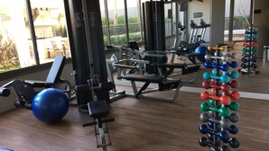 A gym with various exercise equipment, including a bench, a squat rack, and a set of dumbbells. - Brand new, cozy apartment, close to the subway, fast Wi-Fi, Netflix.  (Pinheiros)