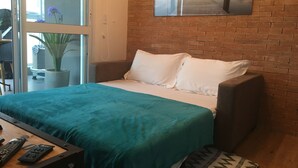 A hotel room with a bed, a potted plant, a painting on the wall, and a view of a dock. - Brand new, cozy apartment, close to the subway, fast Wi-Fi, Netflix.  (Pinheiros)
