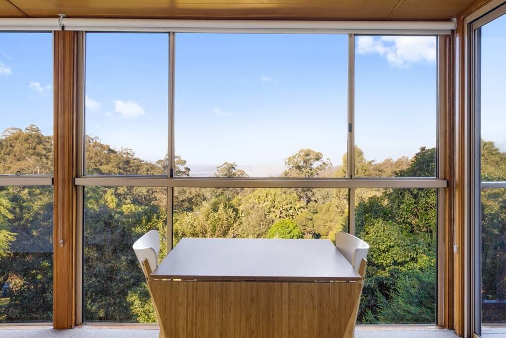 A modern room with a large window offering a view of a forested landscape.