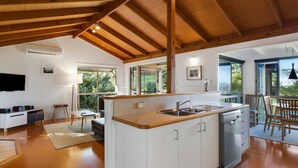 A modern kitchen with white cabinets, a wooden countertop, and a built-in dishwasher. - Windsong at Ravensbourne Escape 3 Bedrooms (Ravensbourne)
