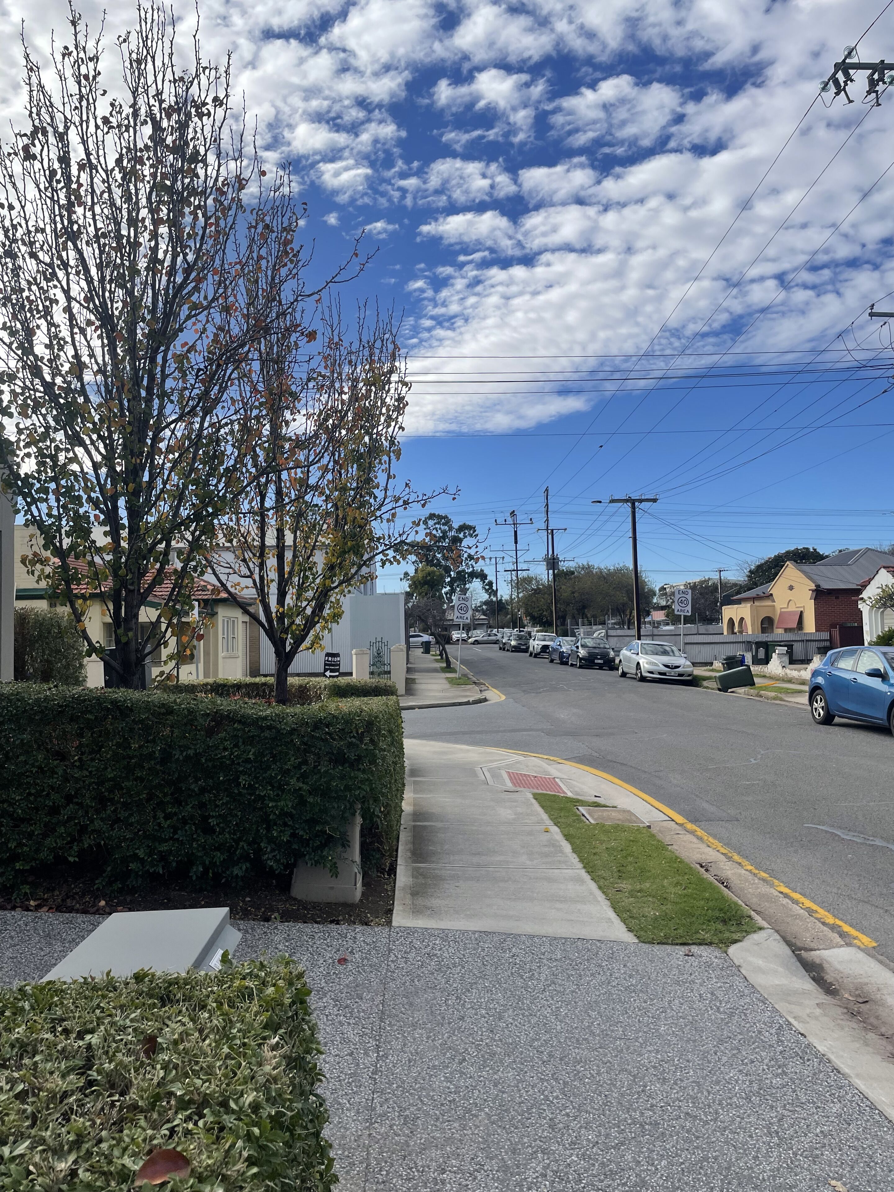 Une vue de rue avec un trottoir, des voitures garées et des immeubles.