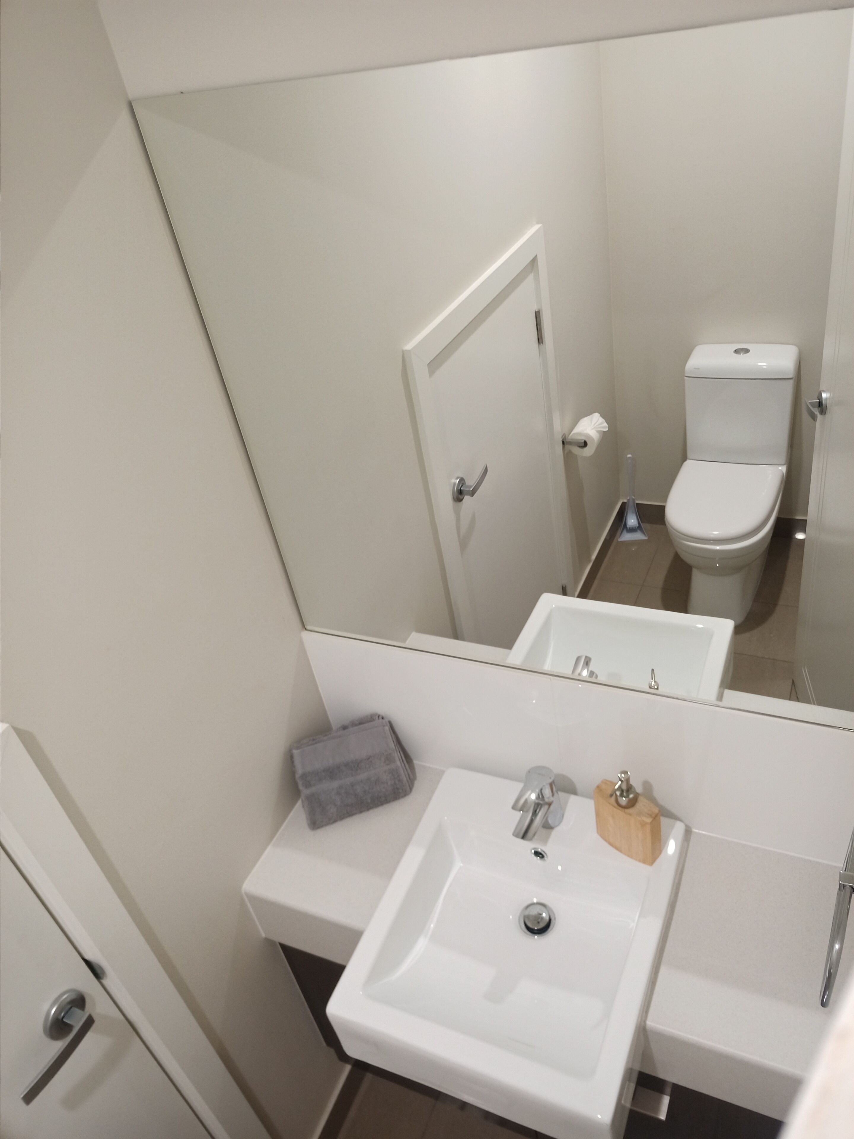 A bathroom with a white sink, mirror, toilet, and a towel on the counter.
