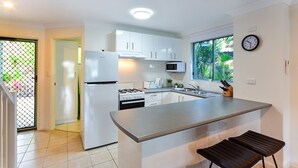 Een moderne keuken met witte kasten, een ingebouwde kookplaat en een groot eiland met barkrukken.