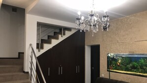 Un salon moderne avec un escalier, un lustre et un aquarium.