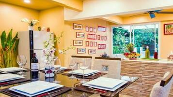 A dining area with a table set for four, a refrigerator, and a window with a view of greenery.