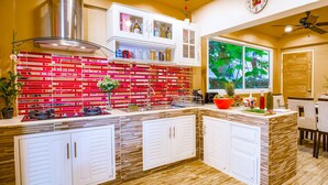 A kitchen with a red and white tiled backsplash, white cabinets, and a window with a view of greenery. - VERY PEACEFUL "EDEN GATE VILLA" CENTRAL CHIANG MAI (Chiang mai)