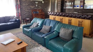 A living room with a sofa, a coffee table, a rug, a wooden cabinet, and a bar area. - Lancelin Beach house (Lancelin)