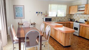A compact kitchen with a central island, a dining table with chairs, and a microwave. - Lancelin Beach house (Lancelin)
