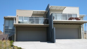 A modern two-story house with a garage, a balcony with a railing, and a small deck area. - Quiet Getaway Only Minutes to Beach (Encounter Bay)