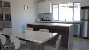 A modern kitchen with a central island, white cabinetry, a stainless steel refrigerator, and a window providing natural light. - Quiet Getaway Only Minutes to Beach (Encounter Bay)