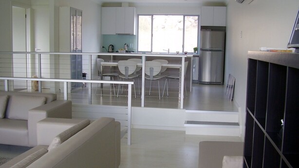A modern kitchen with white cabinets, a stainless steel refrigerator, and a dining area with white chairs. - Quiet Getaway Only Minutes to Beach (Encounter Bay)