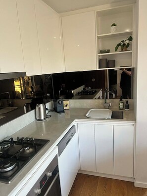 Una cocina moderna con armarios blancos, una estufa de acero inoxidable, un lavavajillas y un fregadero.