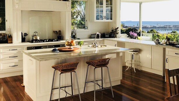 A modern kitchen with a large island, white cabinetry, and a view of the ocean.
