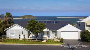 A residential house with a garage, solar panels, and a view of the ocean.