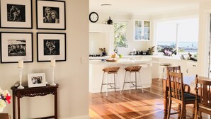 A modern kitchen with a large island, wooden flooring, and a dining area with a wooden table and chairs.