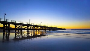 A pier extending into calm waters with a clear sky.