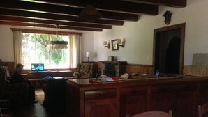 A kitchen with wooden cabinets, a dining table, and a window with curtains. - Charming Swiss house! (V Matilde)