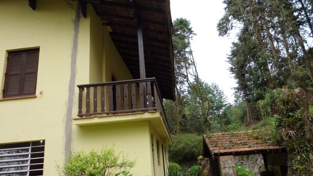 A yellow building with a balcony, surrounded by greenery and trees. - Charming Swiss house! (V Matilde)