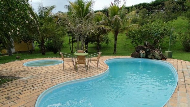 Una piscina con patio de ladrillo y una pequeña mesa con sillas.