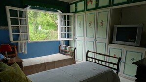 Un dormitorio con dos camas, una ventana con cortinas, un televisor y armarios decorados con motivos florales.