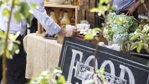 Un étal de nourriture avec un panneau en ardoise, un saladier rempli de fruits et des bouteilles de boissons.