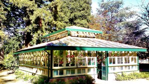 Un petit pavillon d’un seul étage, doté d’un toit végétalisé et de murs blancs, entouré d’une végétation luxuriante et d’arbres.
