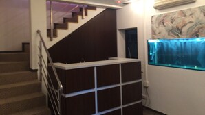 Una escalera con barandilla, un equipo de aire acondicionado instalado en la pared y un acuario.