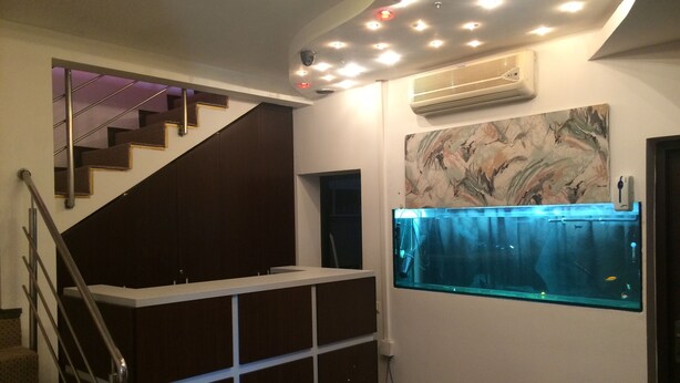 Un interior moderno con una escalera, estanterías empotradas, un equipo de aire acondicionado y un acuario fijado a la pared.