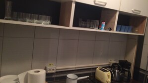 Una cocina con armarios blancos, estufa, tostadora y cafetera.