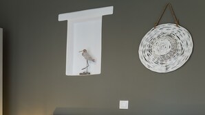 En snyggt bäddad säng med handdukar, en väggmonterad lampa och en vävd väggdekoration.