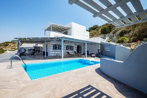 Une villa moderne dotée d’une piscine, d’un espace salon extérieur et d’une pergola.