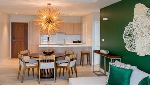 A modern kitchen with wooden cabinets, a central island, and a unique chandelier. - Tiger's Eye - 2-Bed Luxury Suite with Dramatic Ocean Views (Saint George)